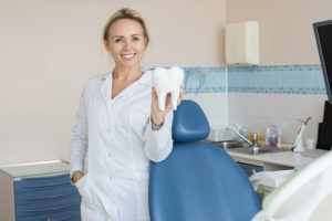 pretty-female-dentist-holding-tooth-model-SVL6WN2